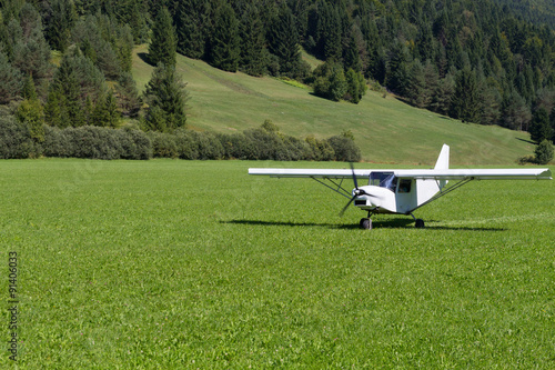Light white aircraft landing on a green meadow, transportation, outdoor