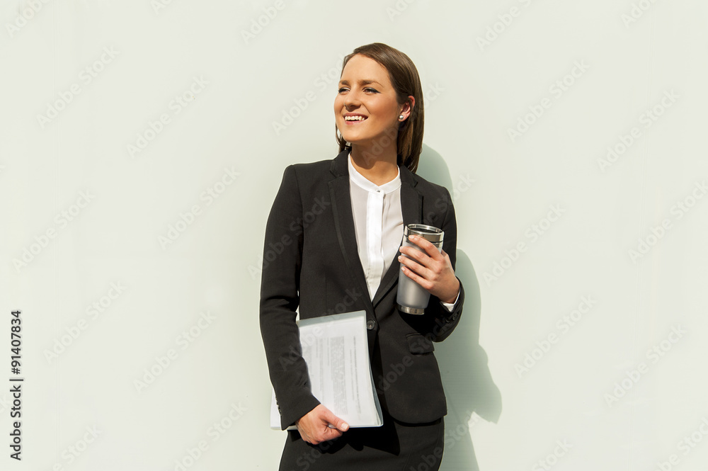 Business woman with documents and coffee standing by white wall Business woman with documents and coffee standing by white wall