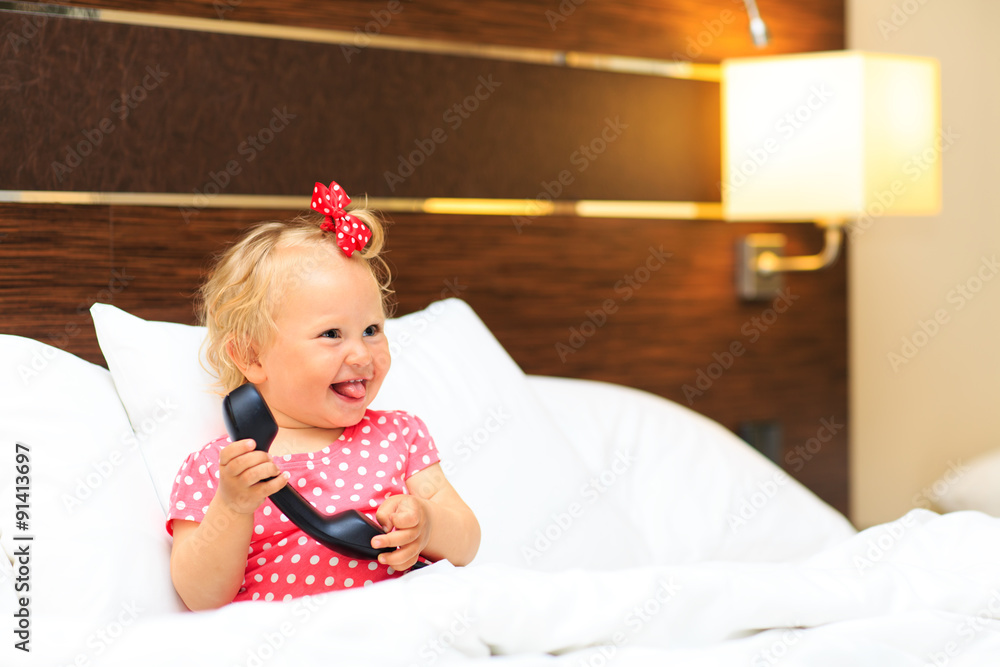 Fototapeta premium cute little girl taking on the phone in hotel room