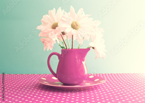Daisies in a red vase over polka dots