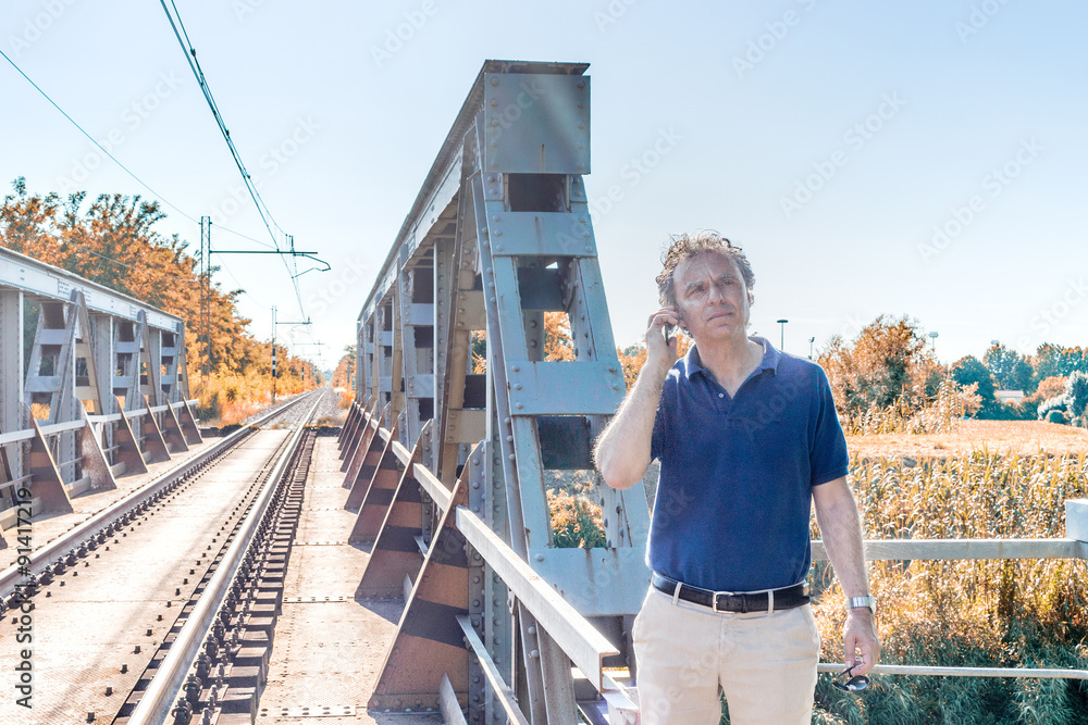 Man on mobile near railroad tracks