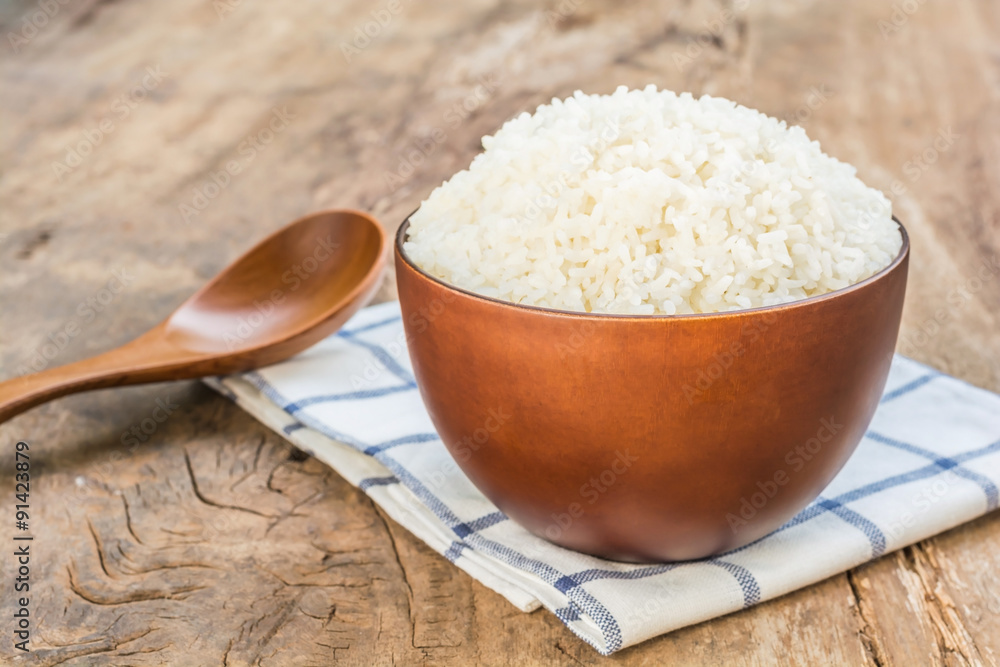 Cooked rice in bowl with spoon and dishcloth on old wooden table Cooked rice in bowl with spoon and dishcloth on old wooden table