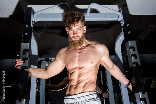 Muscular man with the beard posing in the gym 