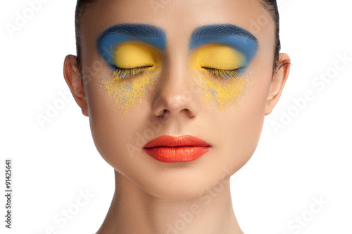 High fashion look, closeup beauty portrait of beautiful young woman model with bright makeup with perfect clean skin with colorful red lips and blue yellow eyeshadows, blue yellow color. High key.