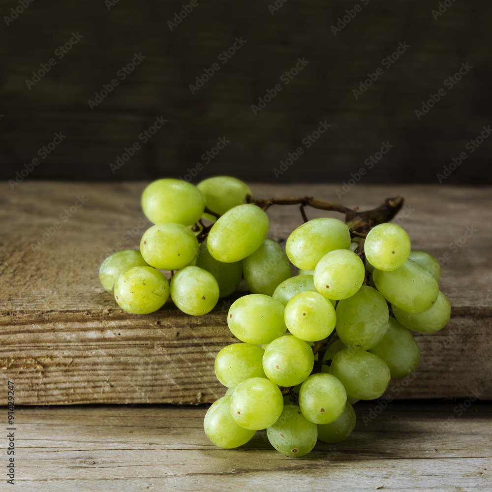 green white wine grapes lying on rustic wood, dark background green white wine grapes lying on rustic wood, dark background