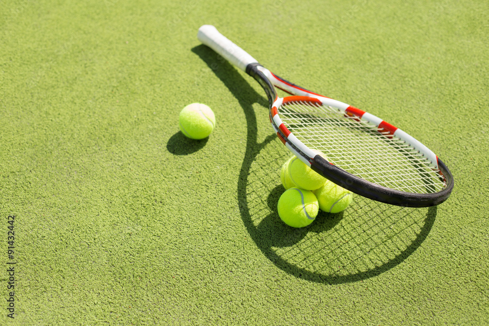 Tennis racket and balls on the court grass