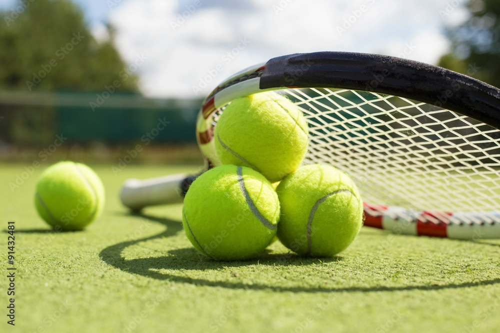 Tennis balls and racket on the grass court Stock Photo