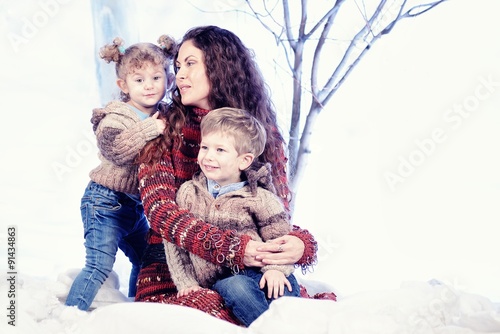Mother, son and daughter on studio snow forest background