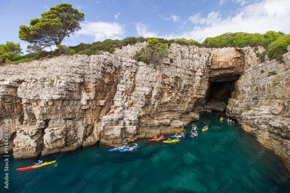 Fototapeta premium Group of kayakers at a sea cave at the Lokrum Island in Croatia.