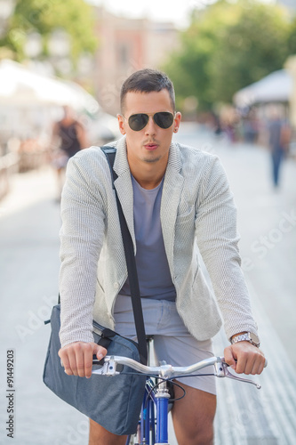 Handsome young businessman riding a bicycle and whistling