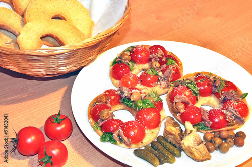 Italian dried bread called friselle with fresh tomatoes, olives, anchovies and basil seasoned with olive oil, oregano and parmesan cheese. Healthy food concept. photo