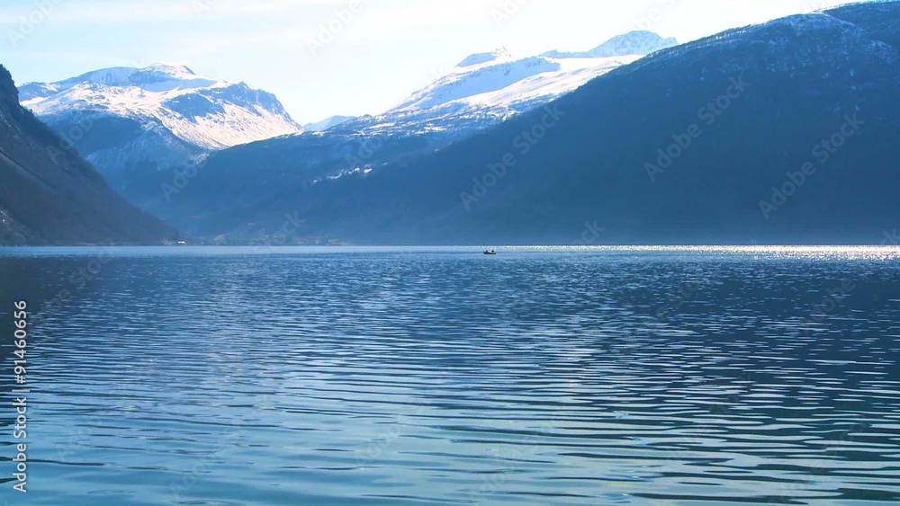 Beautiful wide shot of the fjords of Norway with people in a canoe distant. Beautiful wide shot of the fjords of Norway with people in a canoe distant.