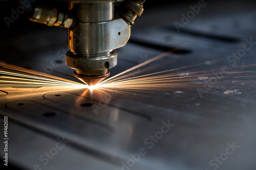 Foto Cutting of metal. Sparks fly from laser