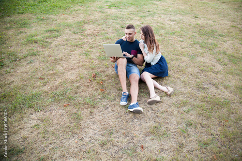Couple sitting with laptop on grass
