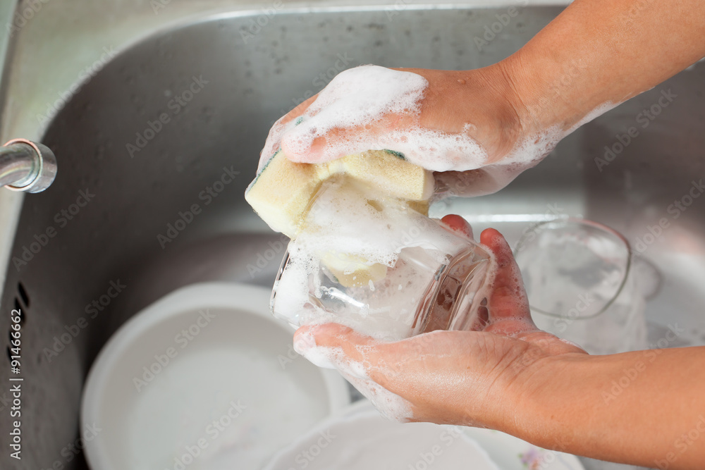 Woman hand washing glass over the sink in the kitchen Woman hand washing glass over the sink in the kitchen