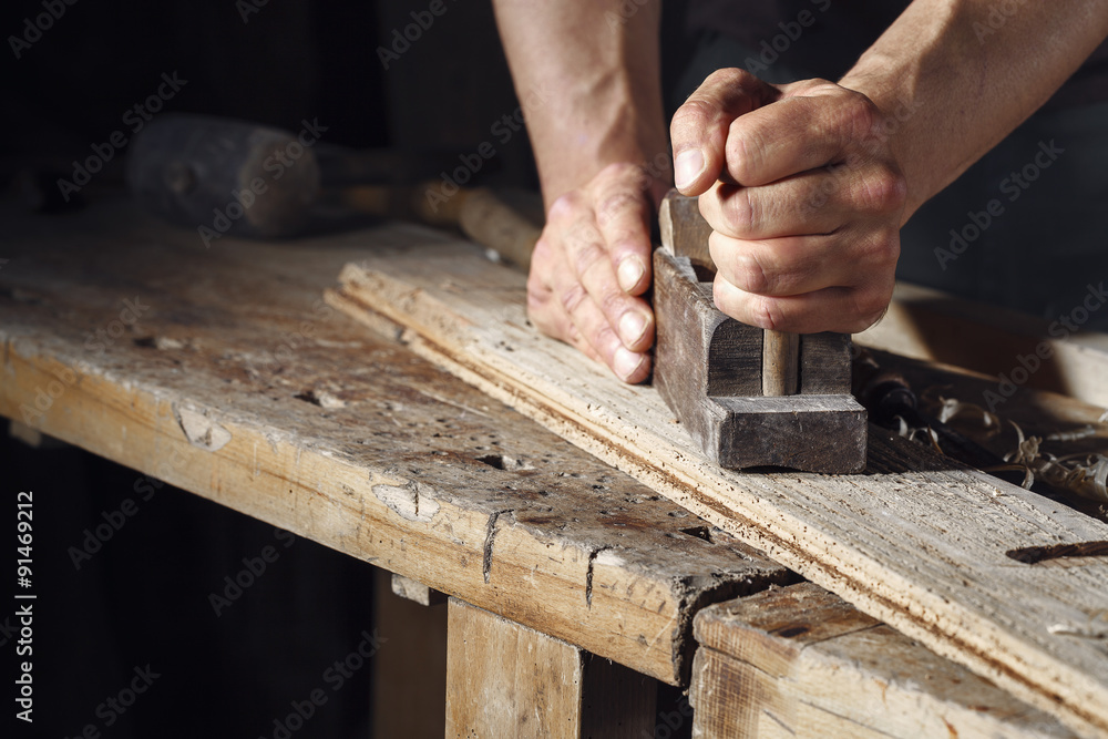 carpenter planing a plank of wood with a hand plane carpenter planing a plank of wood with a hand plane