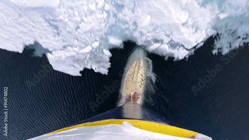 Tilt up bulbous bow point of view of an icebreaker ship plowing through sea ice in Hinlopen Strait in Svalbard Archipelago, Norway.