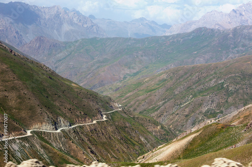 Mountain Valley and Road on Steep Slope Green Grassy Hills Orange Rocks Remote Crests of Tajikistan Remote Area