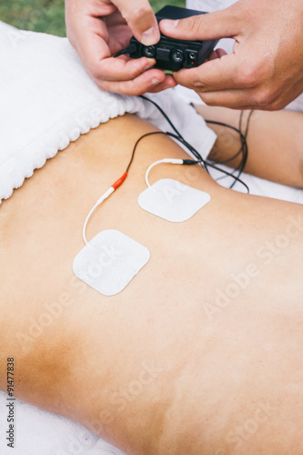 Physiotherapist using electrodes on the back of a patient