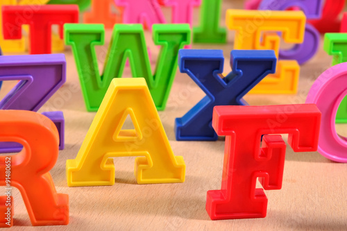 Plastic colorful alphabet letters on a wooden background