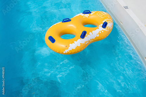 Yellow rubber ring floating on refreshing blue water
