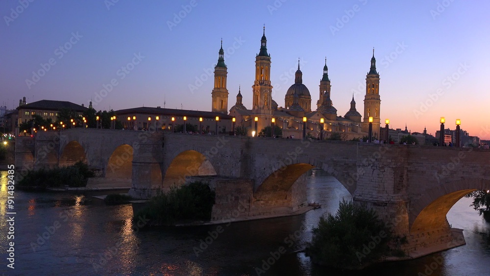 A classic and beautiful stone bridge in Zaragoza, Spain with Catholic cathedral background.