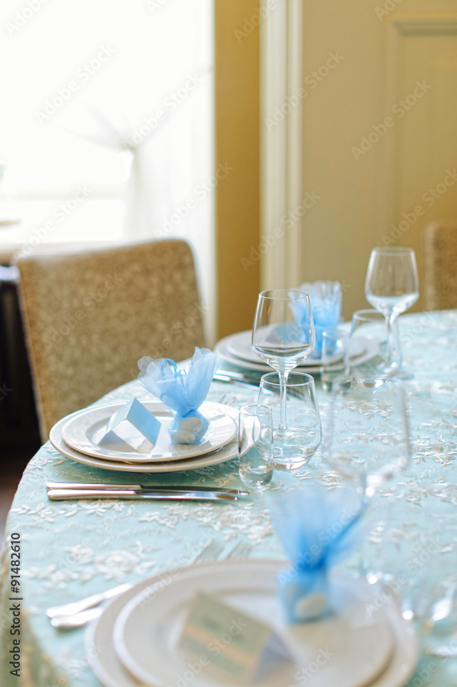Beautifully served table in a restaurant / Beautiful holiday table setting in white and blue color with a gift on the plate