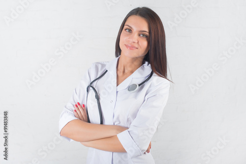 Portrait of woman doctor at hospital corridor, holding tablet computer, looking at camera, smiling.