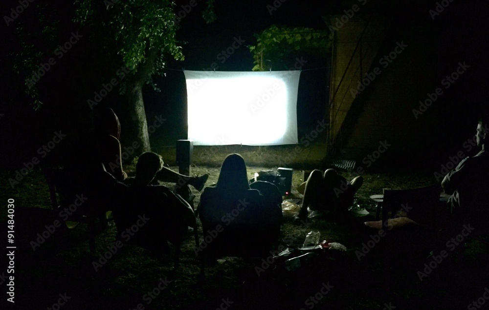 Friends watching movie outside in the yard - obrazy, fototapety, plakaty 