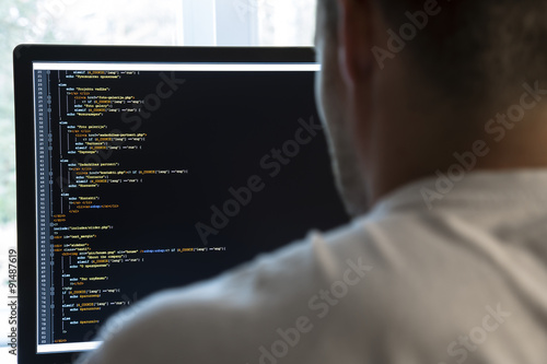 Obraz w ramie programmer from behind and programming code on computer monitor