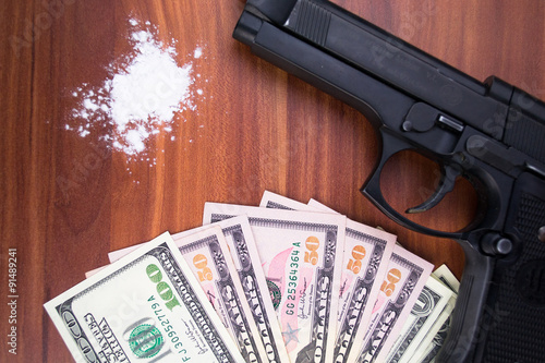 Gun, drugs and money on wooden background photo