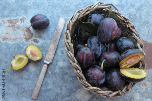 Fresh plums in wooden wicker with old knife
