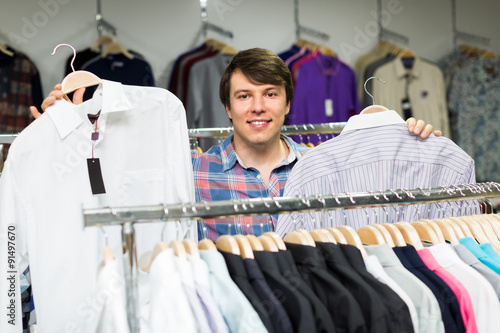 Smiling man choosing shirts in mall