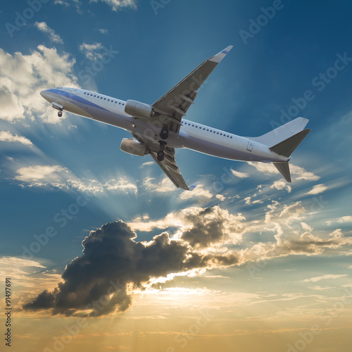 Commercial airplane flying with clouds and sun rays background