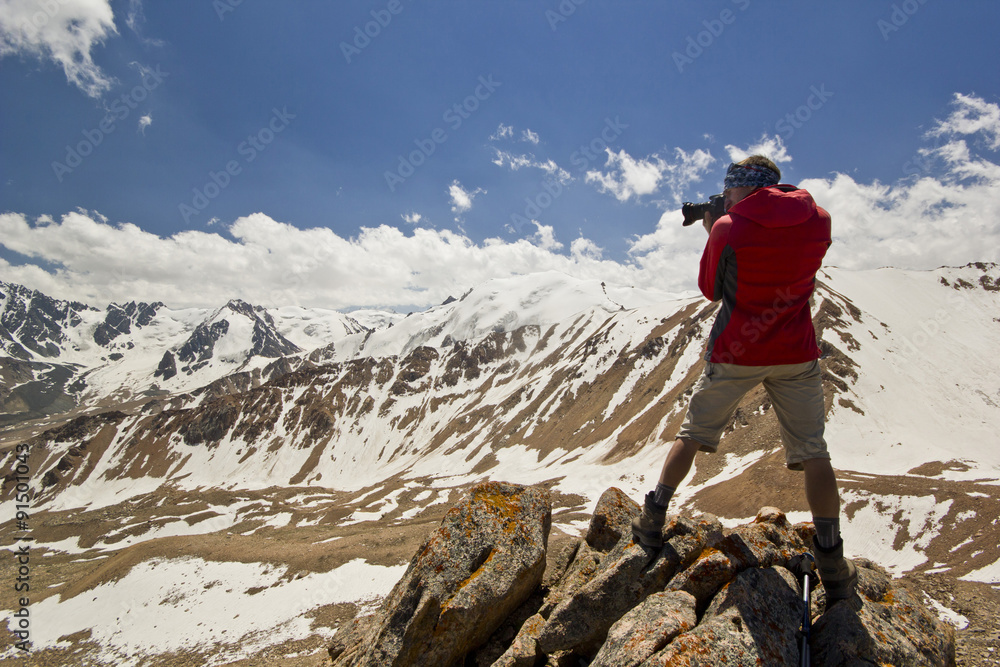 man on a cliff in mountains making photo