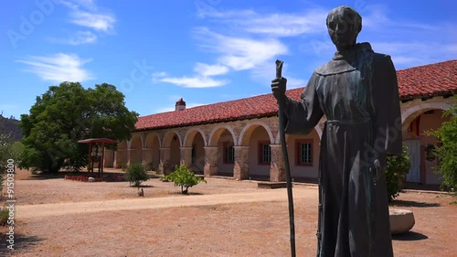 A statue of Father Junipero Serra stands in front of a California Mission. photo