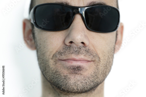 Portrait of a man with a beard wearing dark sunglasses on white studio background