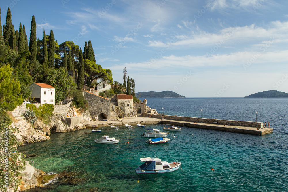 Picturesque view of a port with few boats and old buildings at a small town Trsteno in Croatia.