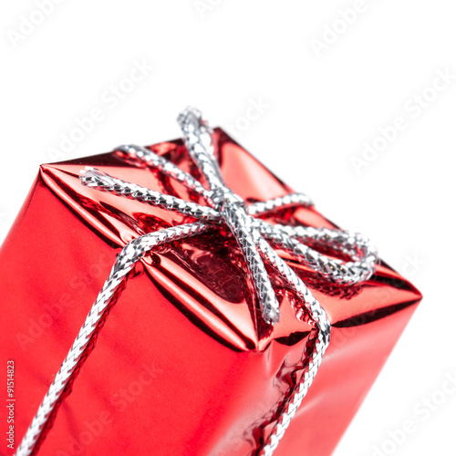 Red gift box with silver ribbon and bow isolated on white macro