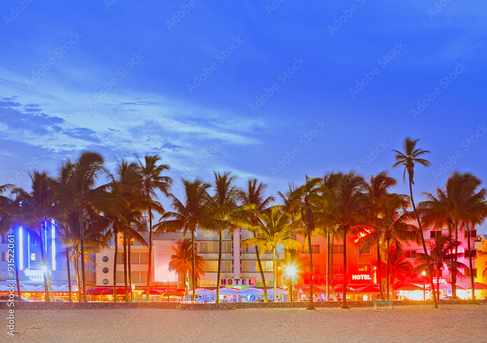 Naklejka Miami Beach na Florydzie, zachód słońca nad oświetloną panoramą hoteli i restauracji w stylu art deco