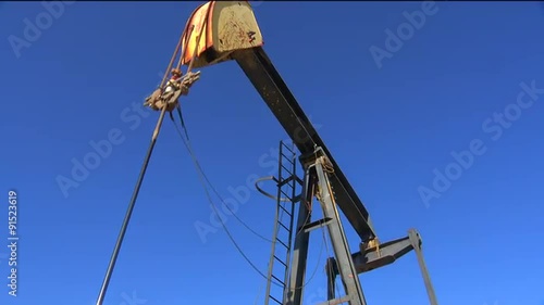 Low angle view in an oilfield of an oil derrick pumping.