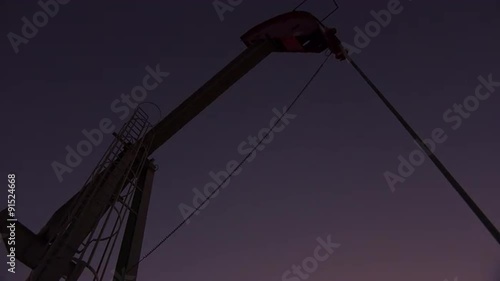 Low of an oil derrick pumping against the night sky.