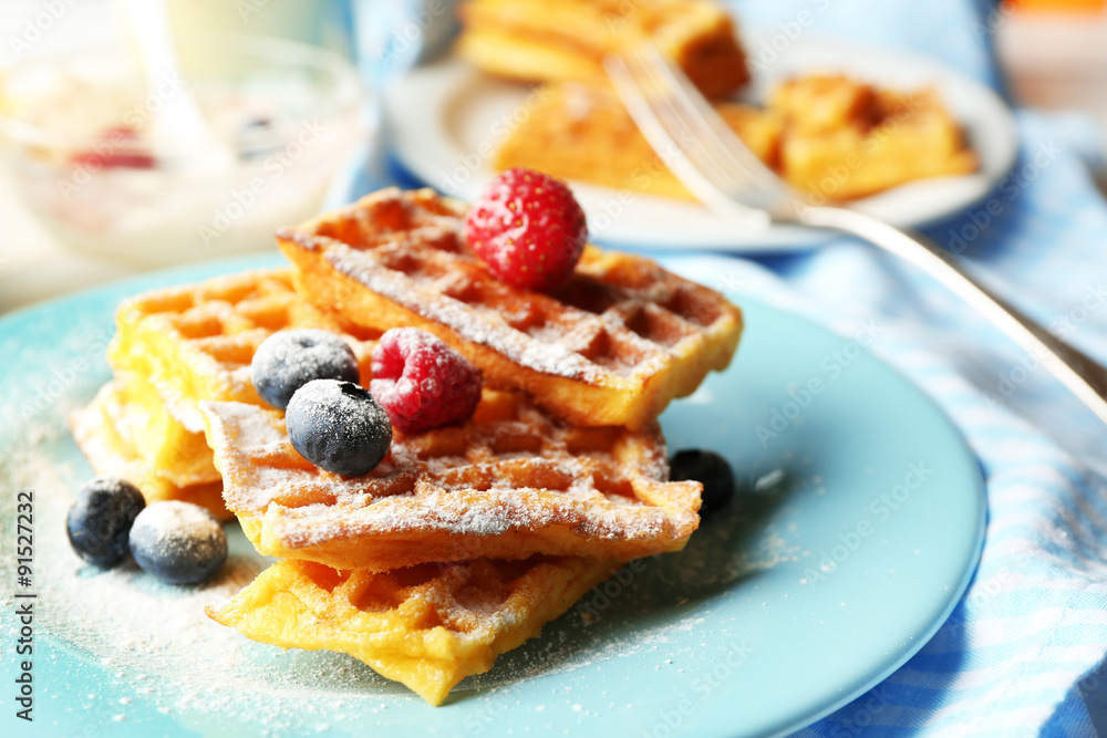 Sweet homemade waffles with forest berries on plate, on light background Sweet homemade waffles with forest berries on plate, on light background