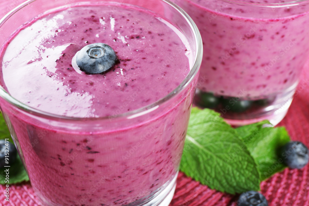 Glasses of blueberry smoothie on pink mat, closeup Glasses of blueberry smoothie on pink mat, closeup