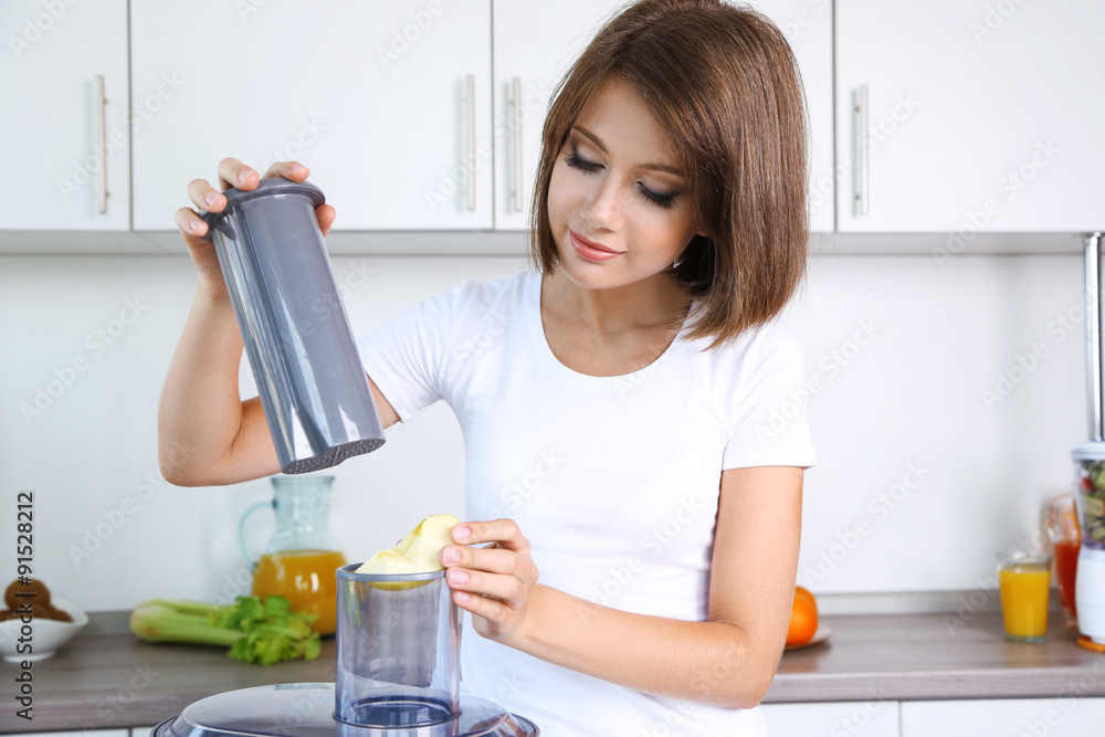 Young beautiful woman using juicer, preparing fresh juice Young beautiful woman using juicer, preparing fresh juice