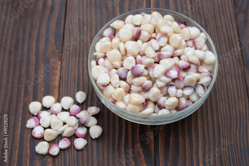 top view corn in glass bowl on wooden background photo