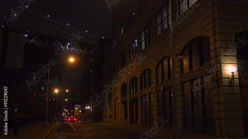 Establishing shot of warehouses under the Brooklyn Bridge with subway train crossing.