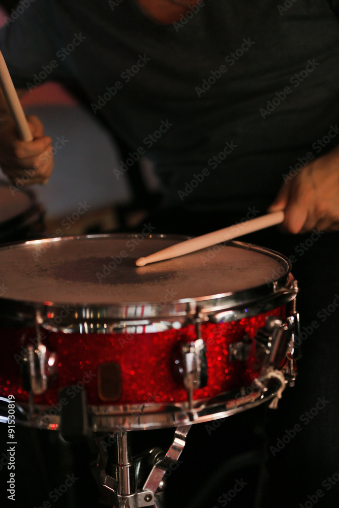 Naklejka premium Drummer with wooden sticks and drums on dark background