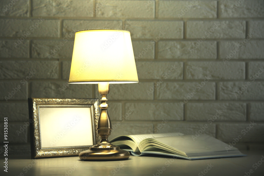 Old fashion table lamp on table on brick wall background Old fashion table lamp on table on brick wall background