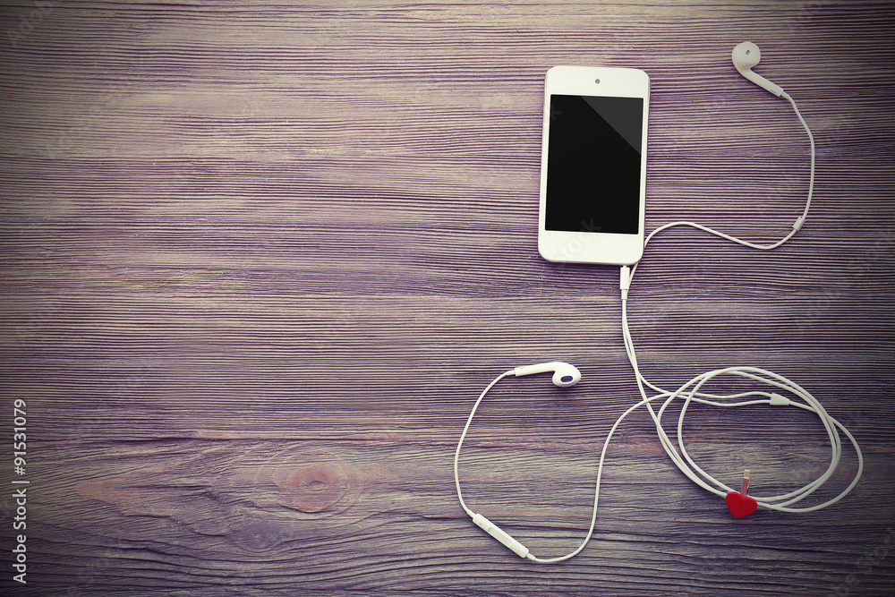 Mobile phone and earphones with red heart on wooden background Mobile phone and earphones with red heart on wooden background